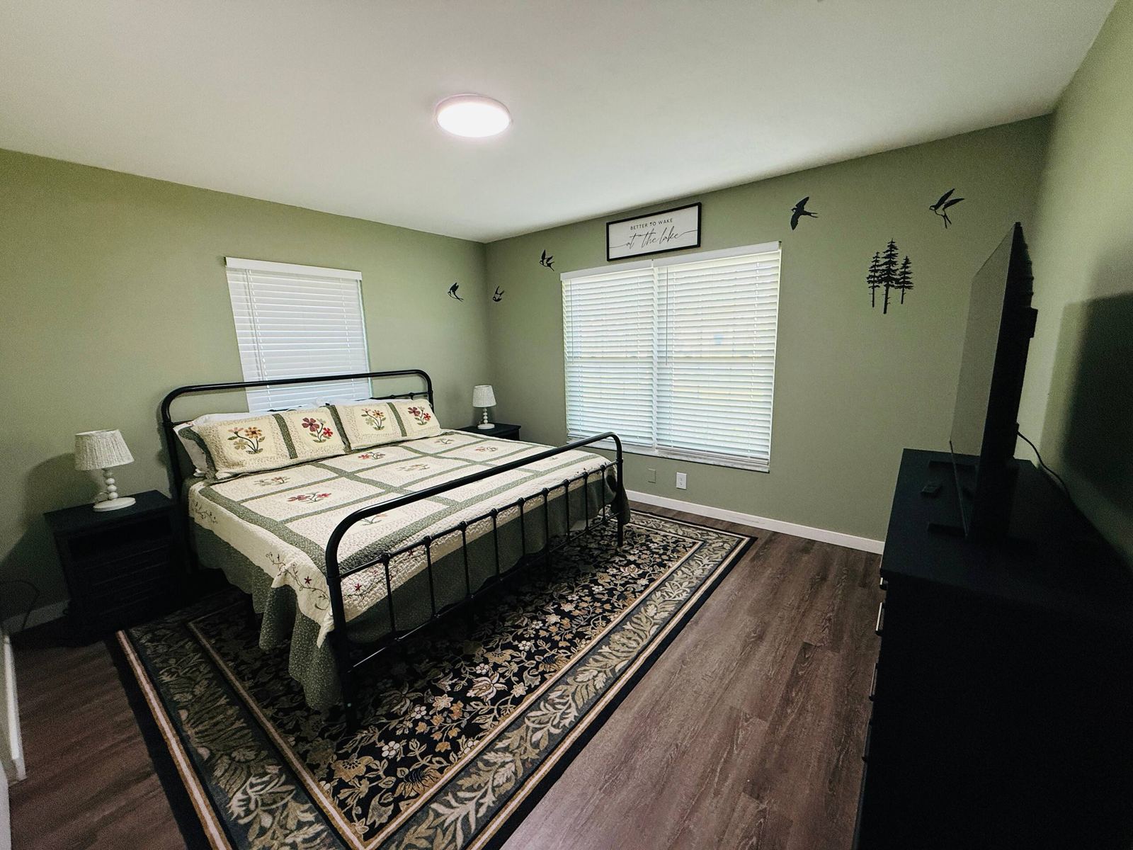 Primary bedroom with king bed, sage green walls, and smart TV